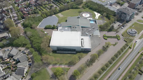 Aerial-of-indoor-sport-center-with-a-solar-panel-field-in-a-suburban-town