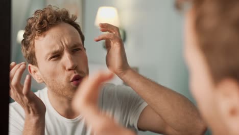 Close-up-portrait-of-a-man-in-the-mirror-taking-care-of-his-problem-skin