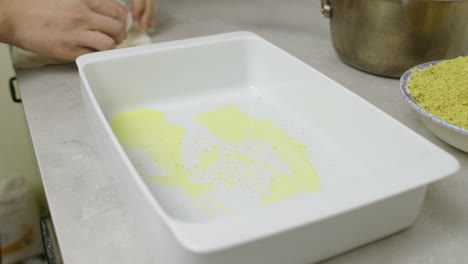 Geschmolzene-Butter-Und-Erste-Teigschicht-In-Die-Keramikpfanne-Geben