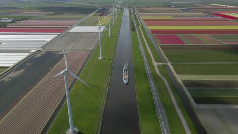 Canal-with-moving-cargo-ship-and-windmills-in-countryside-of-Netherlands
