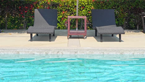 Empty-sun-loungers-on-the-edge-of-a-swimming-pool