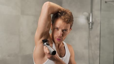 Athletic-man-in-a-T-shirt-shaves-his-armpits-with-an-electric-razor