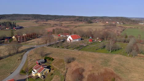 AERIAL---Church-and-cemetery-in-countryside,-Bergum,-Sweden,-wide-shot-forward