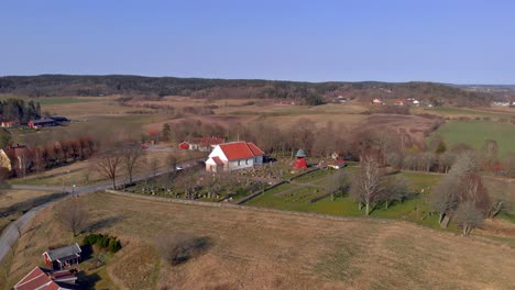AERIAL---Church-and-cemetery-in-countryside,-Bergum,-Sweden,-wide-shot-backward
