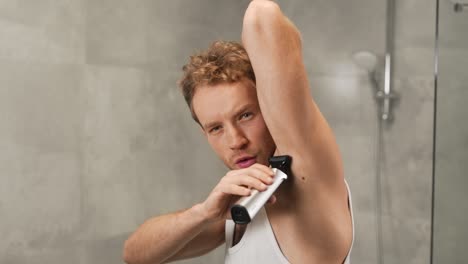 Attractive-young-athletic-man-shaves-armpits-with-electric-cordless-razor
