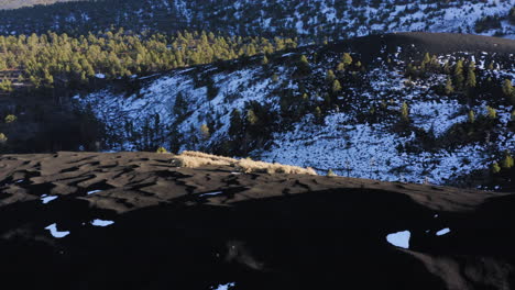 Schwarze-Sanddüne-Mit-Schneebedecktem-Bergtal-Bei-Sonnenuntergang-Krater,-Fahnenmast---Drohnenaufnahme-Aus-Der-Luft