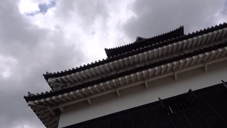 Slow-motion-rotating-shot-looking-up-at-Japanese-Castle-against-cloudy-sky