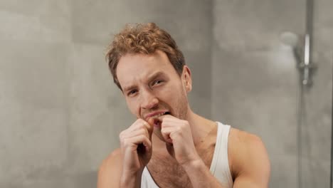 Portrait-of-a-handsome-man-using-dental-floss
