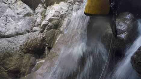 Canyoning-man-in-wetsuit-rappels-in-flow-of-river-canyon-waterfall