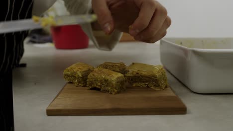 Chef-layers-down-baklava-pieces-onto-wooden-plate