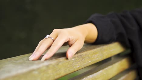 close-up-of-a-model-hand-wearing-diamond-ring-moving-her-fingers-relaxing-on-bench-waiting-no-patience-not-interested-moving-shot-slow-motion-isolated