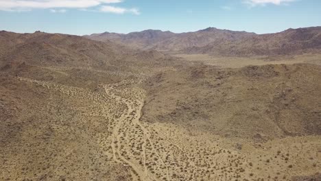 Toma-Aérea-De-Drones-Del-Desierto-Seco-En-El-Parque-Nacional-Joshua-Tree-Durante-El-Día-Soleado-Con-Cielo-Azul-En-California,-Estados-Unidos