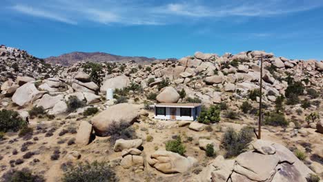 Fly-away-from-small-home-revealing-vast-and-deadly-desert-with-boulders