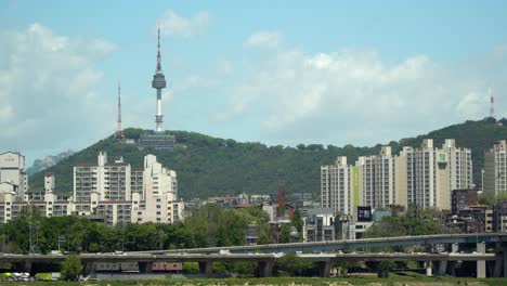 Namsan-Seoul-Tower,-Cars-traffic-on-bridge,-Yongsan-ru-apartments-and-villas-panorama-from-far-point-on-sunny-and-cloudy-day