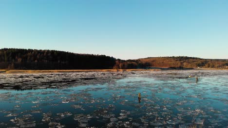 Aufsteigende-Luftaufnahme-Eines-Wunderschönen-Sees,-Der-Bei-Sonnenaufgang-In-Göteborg,-Schweden,-Mit-Schmelzendem-Eis-Bedeckt-Ist