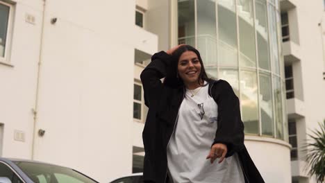 happy-young-attractive-exotic-brunette-with-big-eyes-jumping-spining-around-wearing-black-jacket-white-t-shirt-very-energetic-deep-house-music-video-theme-big-white-building-palm-trees-backround
