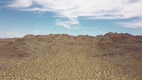 Aufsteigende-Luftdrohnenaufnahme-Der-Endlosen-Wüste-Gegen-Blauen-Himmel-Und-Sonne-Im-Joshua-Tree-National-Park,-USA