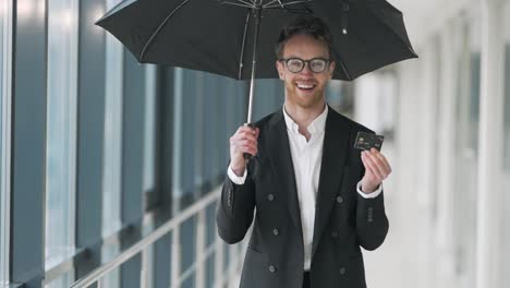 Porträt-Eines-Glücklichen-Geschäftsmannes-Mit-Einem-Regenschirm-Und-Einer-Aktentasche-Aus-Plastik-In-Seinen-Händen