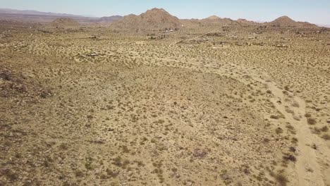 Aerial-flyover-sandy-desert-with-mountains-in-background