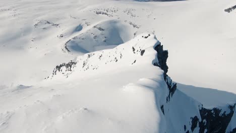 Fliegen-Sie-Den-Majestätischen-Bergrücken-Hinunter,-Der-Mit-Schnee-In-Einer-Fpv-Drohne-Bedeckt-Ist