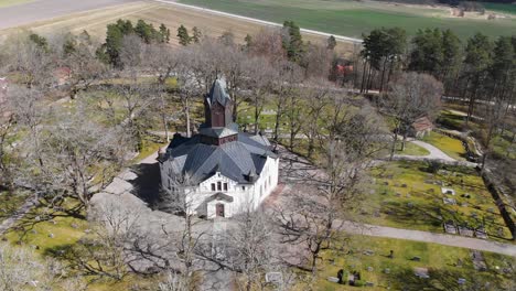 Aerial-panoramic-view-of-Erska-church-surrounded-by-its-peaceful-graveyard-in-a-sunny-countryside