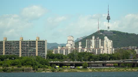 N-Namsan-Seoul-Tower-on-bright-sunny-and-cloudy-day,-view-from-the-bank-of-Han-river-in-Summer