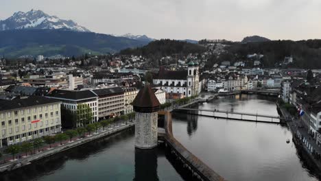 Aerial-view-of-Lucerne,-Switzerland-with-Mount-Pilatus-in-the-background-while-crossing-the-historical-Kapellbrücke-bridge