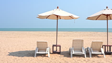 Weiße-Kunststoff-Liegestühle-Unter-Sonnenschirmen-Am-Tropischen-Sandstrand-An-Einem-Sonnigen-Tag