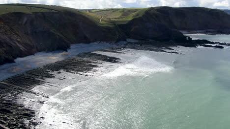 Aerial-shot-of-the-waves-in-the-sea-and-the-rocks-at-Spekes-Mill-coastal-beach-in-Devon