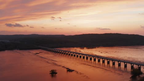 Schöner-Orangefarbener-Sonnenuntergang-Mit-Brücke-über-Den-Breiten-Fluss