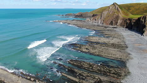 Aerial-shot-of-the-waves-in-the-sea-at-Spekes-Mill-coastal-beach-in-Devon-on-a-sunny-day