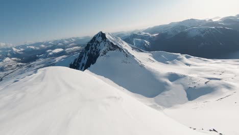 Nahflug-über-Schneebedeckten-Bergrücken-Mit-Spektakulärem-Horizontblick