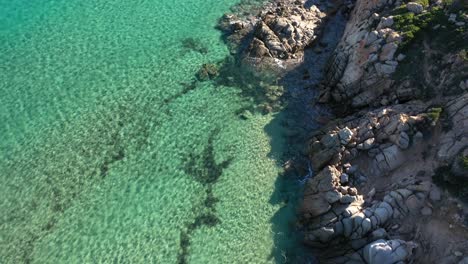 Aerial-shot-of-crystal-clear-turquoise-water-and-rocky-cliffs-in-South-Sardinia,-Italy