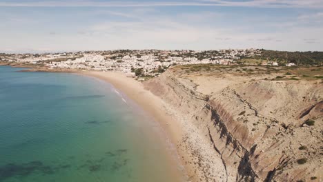 Steep-Limestone-cliff-bordering-Praia-da-Luz-along-Algarve-Coast---Aerial