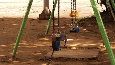 Set-of-kiddie-swings-at-an-old-playground-area-inside-a-residential-suburban-subdivision-in-Mandaue-City,-Philippines