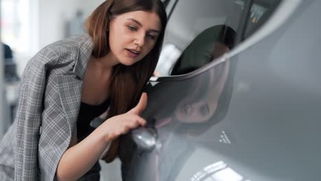 Primer-Plano-De-Una-Mujer-Joven-Inspeccionando-La-Pintura-De-Un-Automóvil