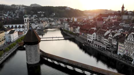 Aerial-view-of-Lucerne,-Switzerland-while-moving-from-Kappelbrücke-bridge-towards-sunset-behind-the-historical-Altstadt