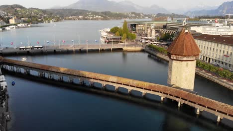 Aerial-footage-with-a-pan-down-view-of-Kapellbrücke-bridge-in-Lucerne,-Switzerland-with-rising-motion-up-above-the-bridge-tower