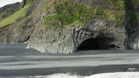 Famous-basalt-pillar-caves-in-Iceland-shore-at-Reynisfjara-beach,-aerial
