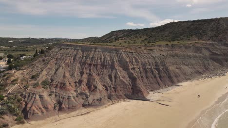 Crane-up-over-Big-cliff-slope-bordering-Praia-da-Luz-flank,-Algarve---Aerial