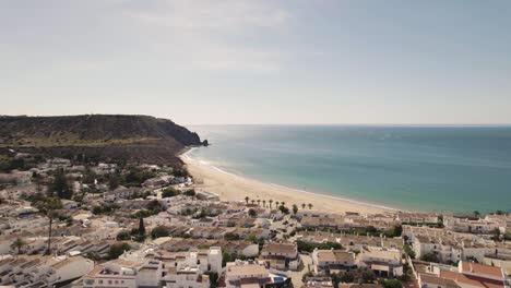 Luz-Picturesque-town-alongside-Algarve-Coastline,-encircling-Praia-da-Luz---Aerial