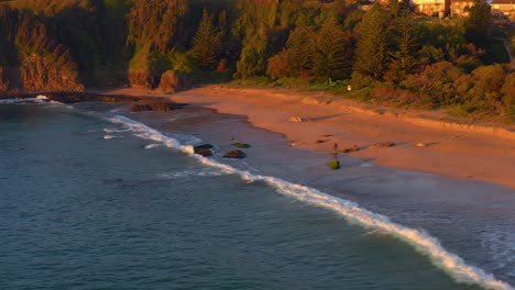 Person-Walking-On-Sandy-Shore-Of-Jones-Beach-During-Sunset-At-Kiama-Downs,-New-South-Wales,-Australia