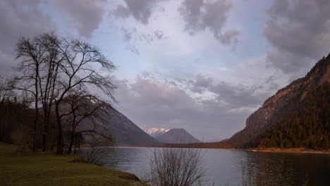 Sonnenaufgangswolken-Bewegen-Sich-über-Einen-See,-Sylvensteinsee-Bayerische-Alpen-Bayern-Deutschland