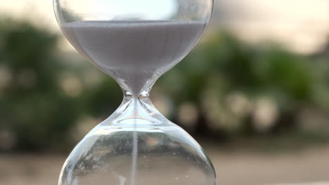 Hourglass-as-time-passing-on-wooden-table-with-bokeh-background