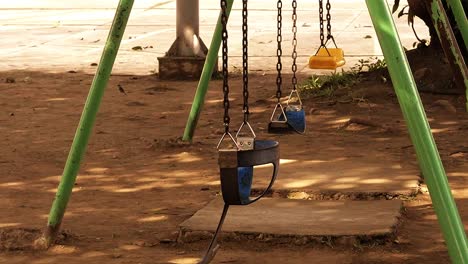 Set-of-kiddie-swings-at-an-old-playground-area-inside-a-residential-suburban-subdivision-in-Mandaue-City,-Philippines