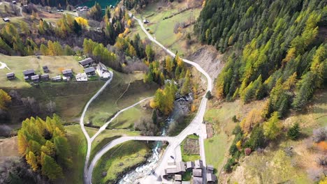 Aerial-footage-above-Swiss-village-in-autumn-:-fall-with-mountains-and-a-river-on-the-background