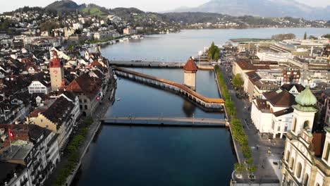 Aerial-view-of-Lucerne,-Switzerland-from-up-high-while-moving-from-the-Jesuit-church-over-Kappelbrücke-bridge-towards-the-lake