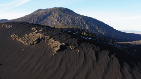 Schwarze-Sanddüne-Mit-Vulkanischem-Berg-Bei-Sonnenuntergang-Krater,-Fahnenmast---Luftdrohnenflugaufnahme