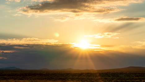 Rays-of-sun-pierce-the-clouds-as-the-sunrise-lights-the-Mojave-Desert-landscape---static-time-lapse