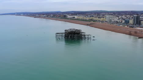 An-aerial-shot-flying-over-West-pier-ruin-in-Brighton-on-the-coast-coast-of-England-with-seagulls-flying-about